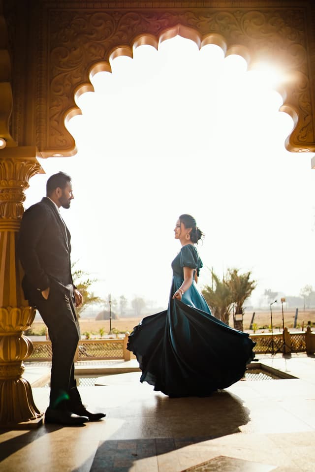 Couple standing beneath an ornate arch in warm evening light