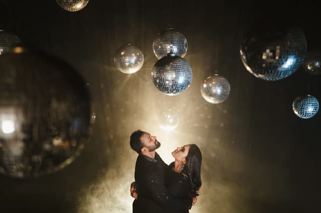 Couple standing beneath mirrored lights in a cinematic portrait