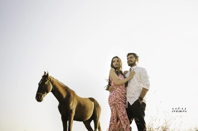Couple standing beside a horse in a bright editorial portrait