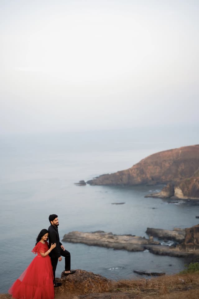 Couple posed on a coastal hillside with water in the distance