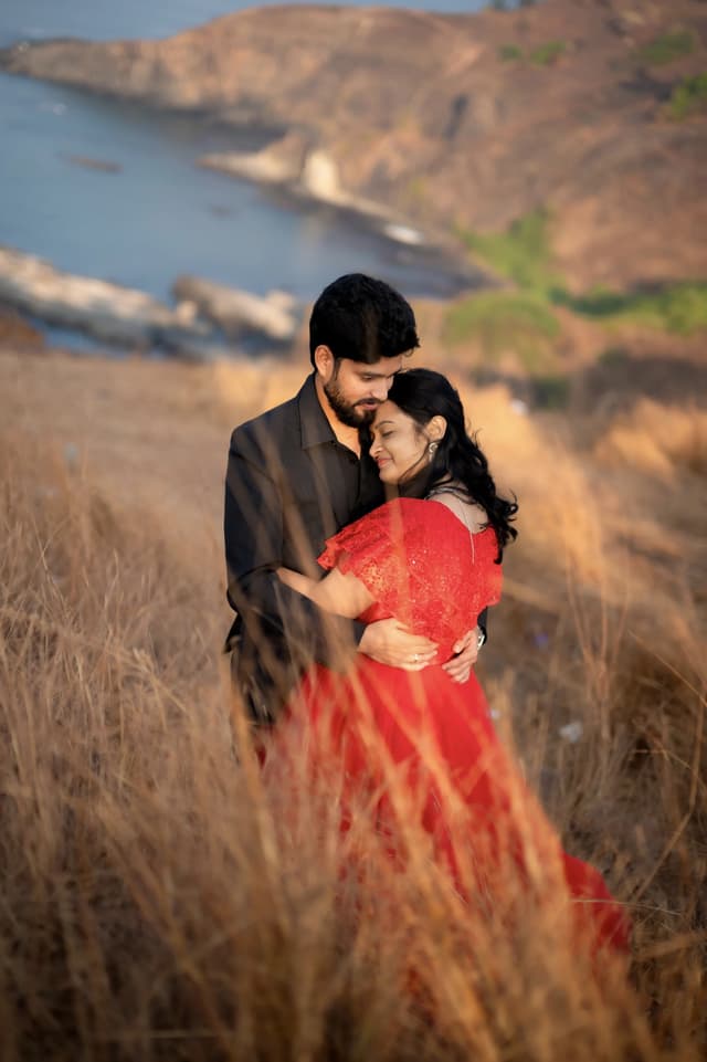 Couple standing close in red and black outfits on a hillside