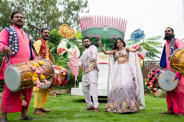 Couple walking with drummers during a colorful Haldi celebration