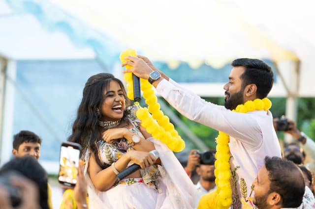 Groom lifting a yellow garland during a joyful Haldi moment
