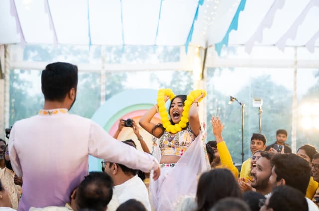 Guests raising a yellow garland during a Haldi ceremony