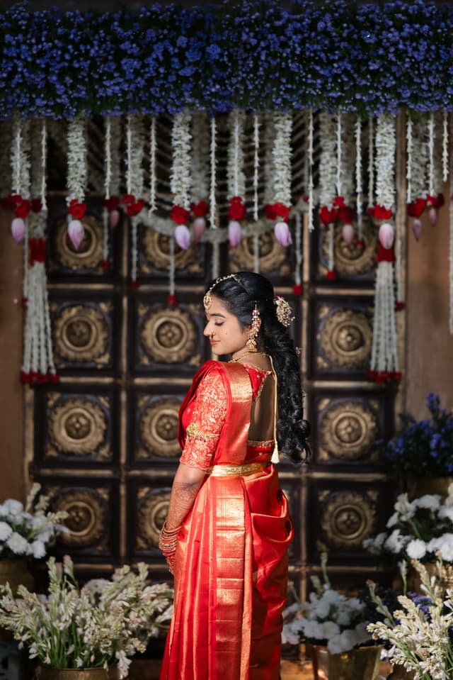 Bride standing before a traditional carved backdrop for Pellikuthuru