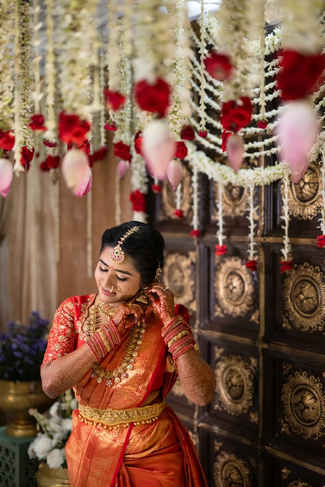 Bride adjusting jewelry beneath hanging floral decor
