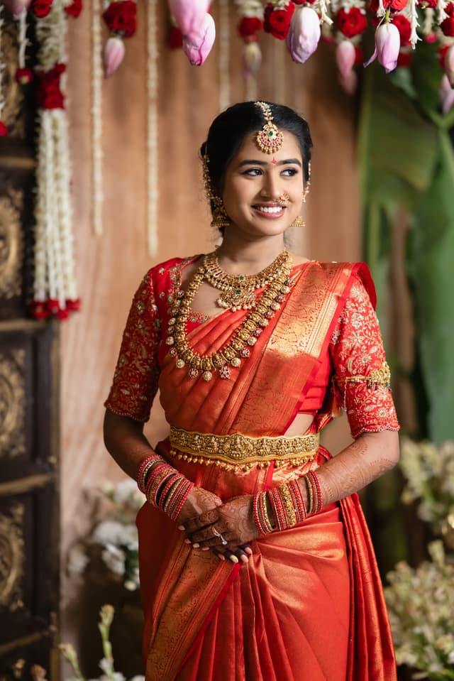 Bride smiling in a red sari during a Pellikuthuru portrait