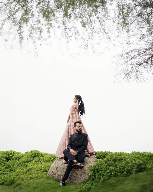 Couple in formal Sangeeth attire posed beneath an open tree canopy
