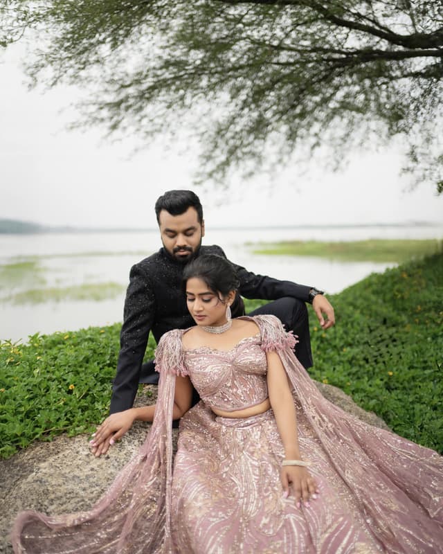 Couple seated together by a lakeside in coordinated Sangeeth outfits