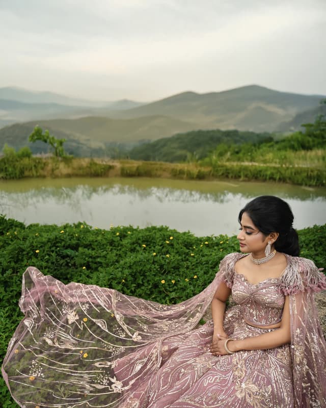 Bride seated beside a lake with hills in the distance