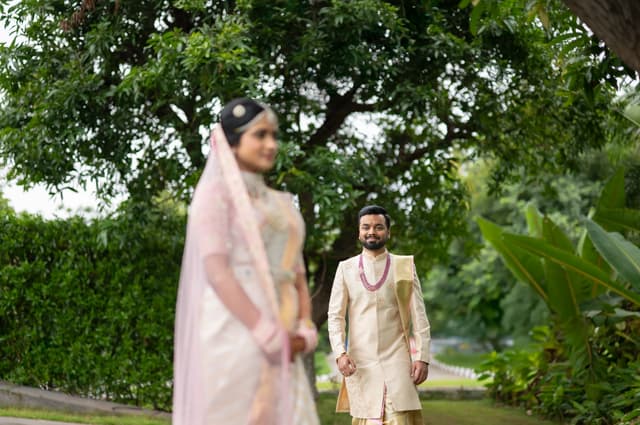 Bride and groom separated by greenery in an editorial wedding portrait