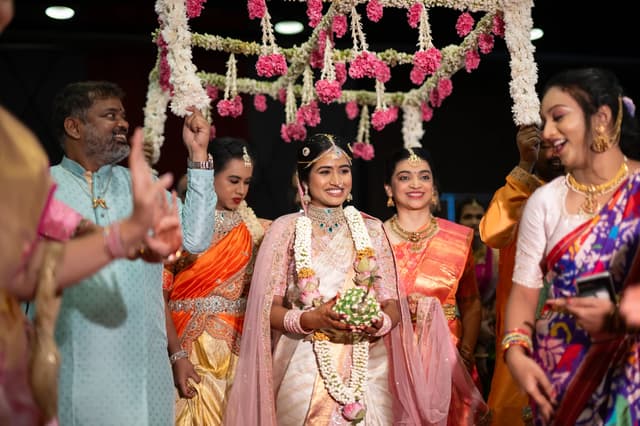 Bride walking with family beneath floral decor during a wedding celebration