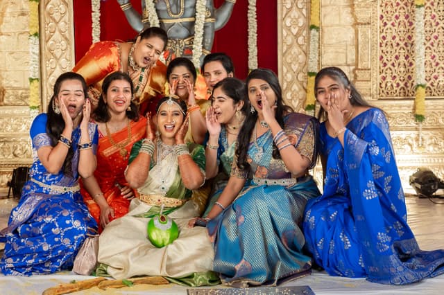 Bride seated with friends in bright blue outfits during a wedding celebration