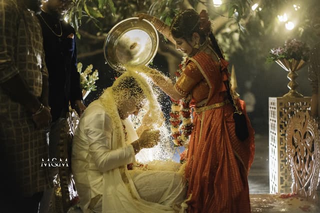 Ceremony moment lit by firelight as family pours water over the groom